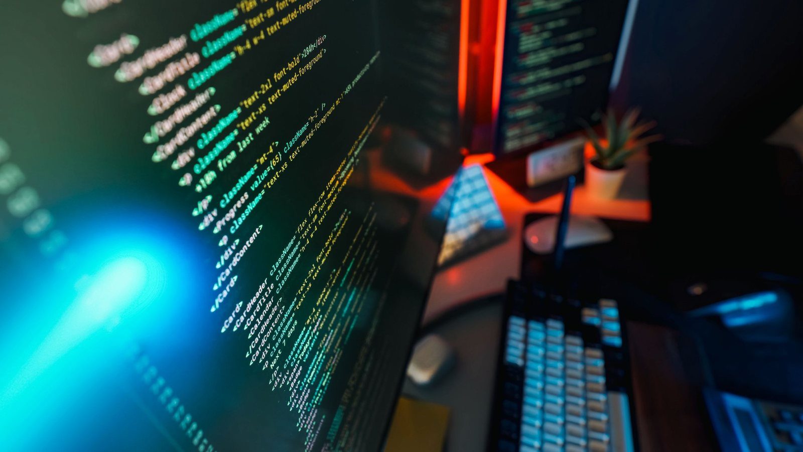 Code on a monitor beside a mechanical keyboard on a home desk