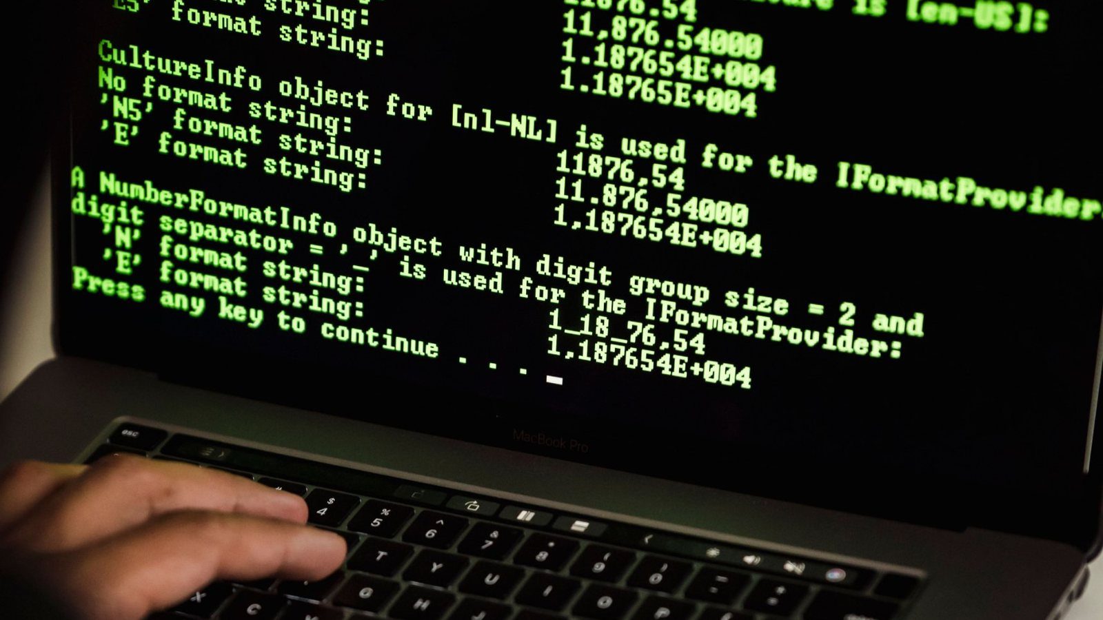 Hands on a laptop keyboard with green terminal output on screen