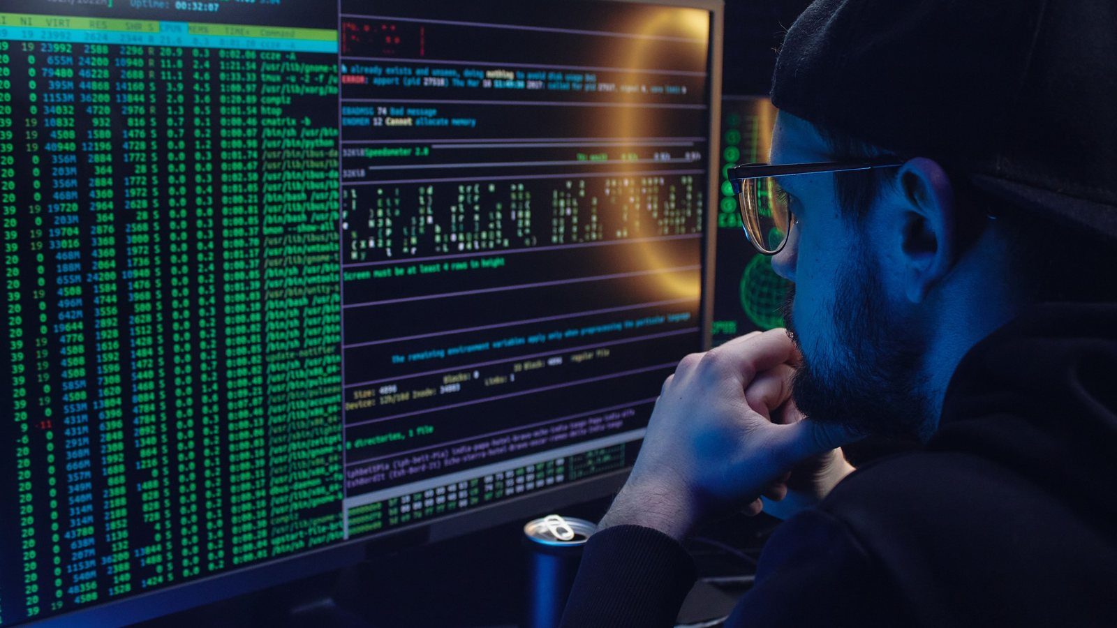 A man studying a monitor showing a Linux process list and terminal output