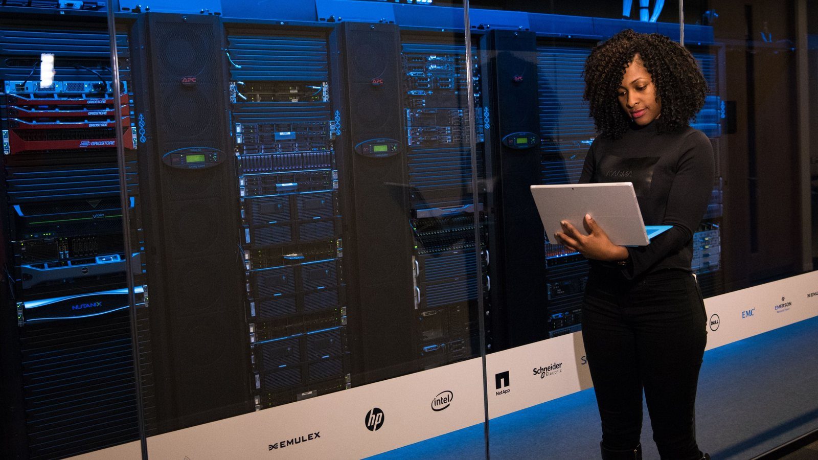An IT professional with a laptop in front of server racks in a data centre